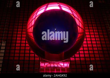 Glass ball photographed on a perforated plate with red light. Stock Photo
