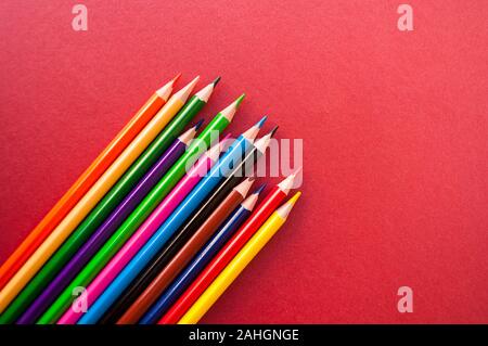 Colorful pencils on red background with copyspace. Stock Photo