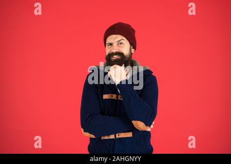 Personal stylist. Warm and comfortable. Fashion menswear shop. Masculine clothes concept. Think and decide. Winter menswear. Man bearded warm jumper and hat red background. Winter season menswear. Stock Photo