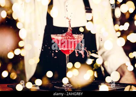 Barman in making cocktail at a nightclub. Nightlife concept. No face. Pouring into glass.. Horizontal with festive bokeh lights Stock Photo