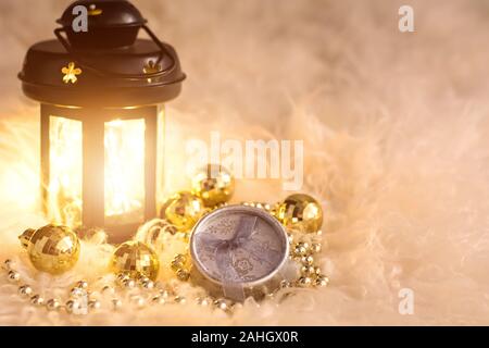 New Year's toys on white fur. Lantern, gold beads, gift box and disco balls. Christmas composition. Stock Photo