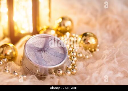 New Year's toys on white fur. Lantern, gold beads, gift box and disco balls. Christmas composition. Stock Photo