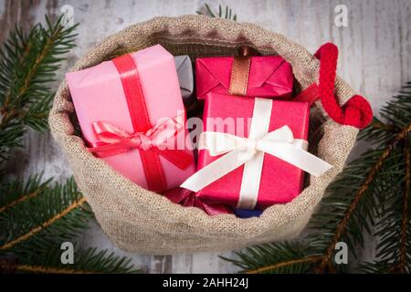 Wrapped gifts for Christmas, birthday or other celebration in jute bag and spruce branches Stock Photo