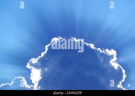 Stunning blue grey cumulus cloud with sunbeams in the backdrop Stock Photo