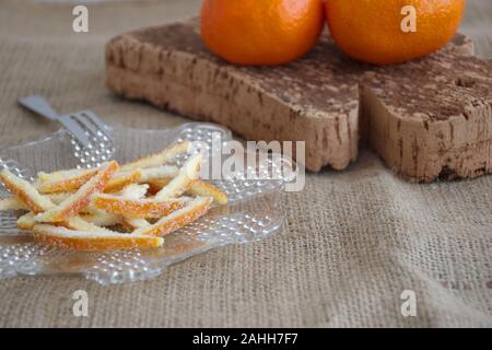 Candied orange peel on plate and oranges on cutting board Stock Photo