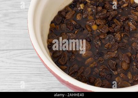 Mixed dried fruit soaking in a tea marinade in a mixing bowl. Grey wood background Stock Photo