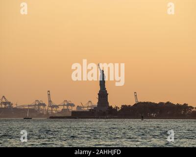 Liberty island, New York City - Statue of Liberty on Hudson river during cruise sunset at dusk Stock Photo