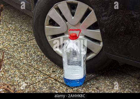 Windscreen washer antifreeze stands in front of the wheel of a black car Stock Photo