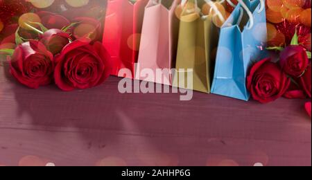 Colorful shopping bags and roses on wooden table Stock Photo