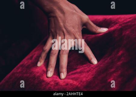 Black skin hand touching the red carpet fur on a chair make some bright red light Stock Photo