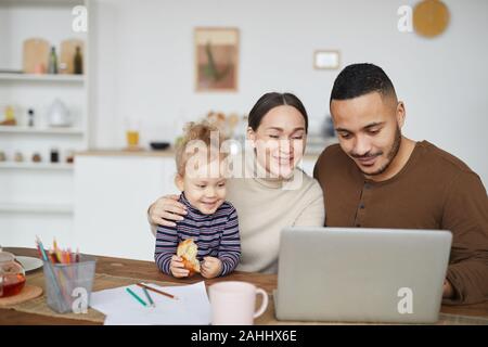 Portrait of smiling mixed race family using laptop together while shopping online, copy space Stock Photo