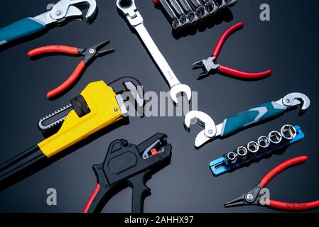 Mechanic tools on black background. Set of pipe wrench, bent wrench, nuts, spanner, pliers, and chrome combination wrenches. Service technician tools Stock Photo