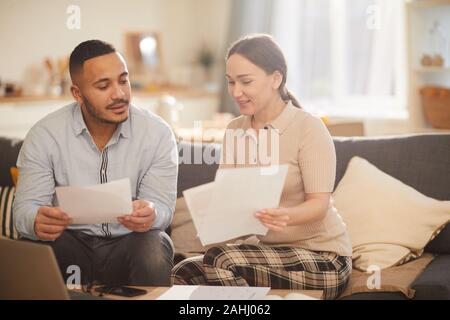Portrait of adult couple doing paperwork while paying taxes online in cozy home interior, copy space Stock Photo