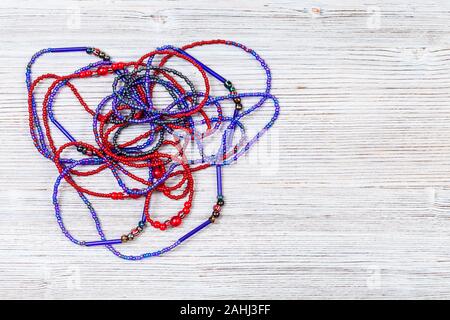 needlecraft background - top view of hand crafted tangled necklace from glass beads on gray wooden board with copyspace Stock Photo