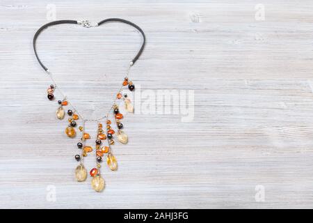 needlecraft background - top view of hand crafted necklace decorated by chains with natural citrine and cornelian gemstonesa and pearls red on gray wo Stock Photo