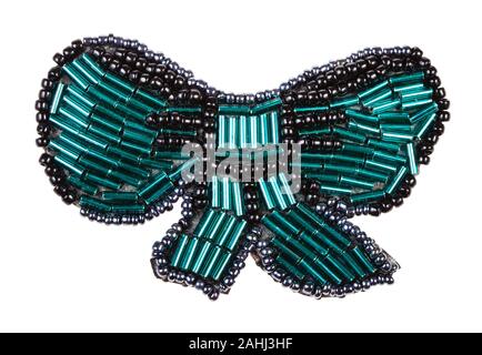 hand crafted bow tie shaped brooch from glass green bugles and black beads isolated on white background Stock Photo