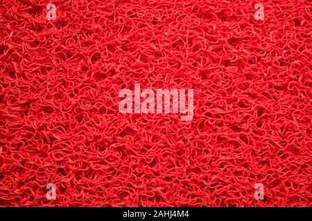 Red synthetic carpet flooring texture or background concept. Stock Photo