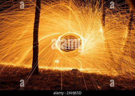 Fire circle spinning from steel wool creating spiral spark, Steel wool spinning fire circle spinning from steel wool creating spiral spark, birch grov Stock Photo