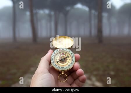 A person disoriented by the fog tries to find the right path with a compass Stock Photo