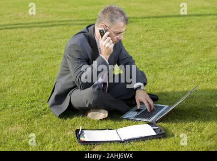 Geschäftsmann sitzt auf einer Wiese, telefoniert, Laptop, Computer, MR:Yes