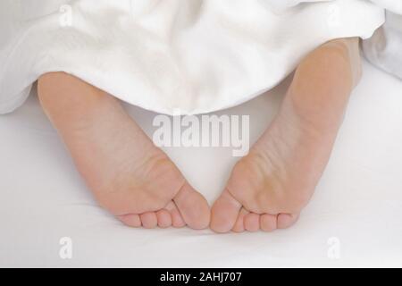 25 -30 jährige Frau schläft im Bett, zeigt ihre Füsse, MR:Yes