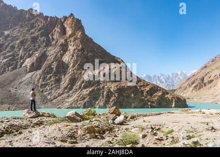 Attabad Lake Landscape Picturesque Breathtaking View with a Pakistani Young Man Enjoying the Panorama on a Sunny Blue Sky Day Stock Photo