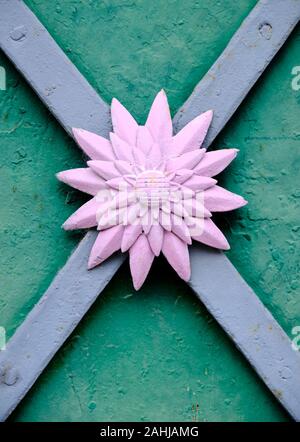 Vintage flower shaped metal door feature.  Made of pink metal, over x cross intersection Stock Photo