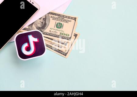 NY, USA - DECEMBER 26, 2019: Tiktok paper logo lies with envelope full of dollar bills and smartphone Stock Photo