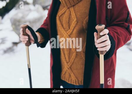 Woman holds trekking poles for Nordic walking with snow on background, High Tatra mountains, Slovakia Stock Photo