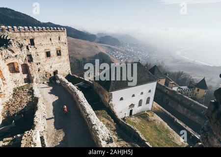 Woman in red coat discovering Lubovniansky Hrad castle ruins in Stara Lubovna, Slovakia. Stock Photo