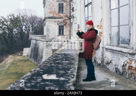 Woman in red coat taking picture of old Pidhirtsi Castle in Lviv region, Ukraine Stock Photo