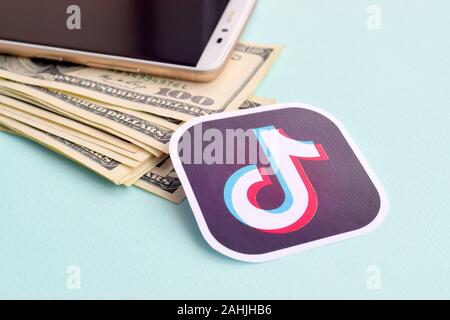 NY, USA - DECEMBER 26, 2019: Tiktok paper logo lies with envelope full of dollar bills and smartphone Stock Photo