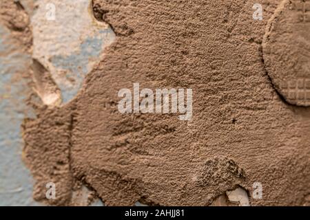 Tiled wall. Preparation for repair. Broken and gritty surface. Rough texture of blue color with brown spots. Stock Photo