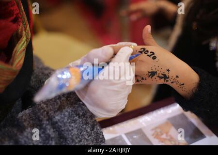 Gaza City, The Gaza Strip, Palestine. 30th Dec, 2019. A Palestinian girl welcoming the new year by drawing a Henna Tattoo with the new year numbers 2020 on her hand at Gaza city Credit: Majd Abed/Quds Net News/ZUMA Wire/Alamy Live News Stock Photo