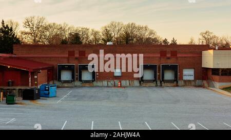 Establishing shot of an empty warehouse building with cargo loading dock and parking lot. Stock Photo