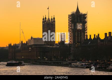 Westminster, London, 30th Dec 2019. The new blue and gold-leaf coloured clock face of the Elizabeth Tower is visible on the Houses of Parliament,  silhouetted at sunset. A beautifully sunny winter day in London concludes with a soft pastel sunset in Westminster. Credit: Imageplotter/Alamy Live News Stock Photo