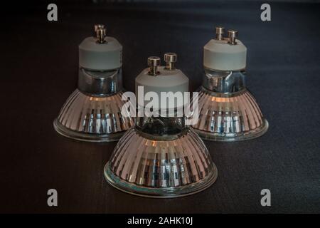 Three halogen light bulb units facing down on a black background indoors close up Stock Photo
