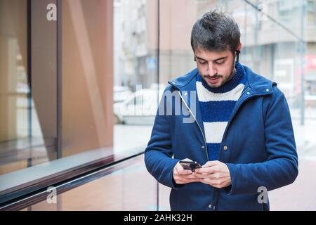 Handsome young man, walking in city street using mobile phone . Stock Photo