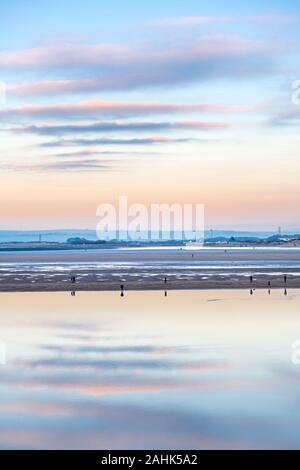 Appledore, North Devon, England. Monday 30th December 2019. UK Weather. After a sunny day with broken cloud in North Devon, at dusk there's a chill in the air as tourists enjoy the last rays of sunlight walking on the beach at low tide in Instow. Terry Mathews/Alamy Live News. Stock Photo