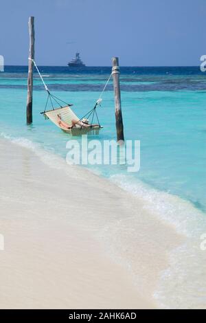 woman wearing a bikini and a hat, relaxing in a hammock in the sea at Bandos Island, Maldives, Indian Ocean Stock Photo