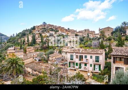 Stunning cityscape of the small coastal village Deia in Mallorca, Spain. Traditional houses located in terraces on the hills surrounded by green trees. Spanish tourist destinations. Stock Photo