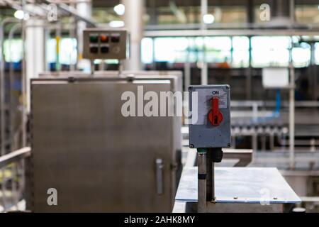 on and off industrial red switch in on position selective focus, packaging machine, belt conveyor system brewhouse brewery factory machines background Stock Photo