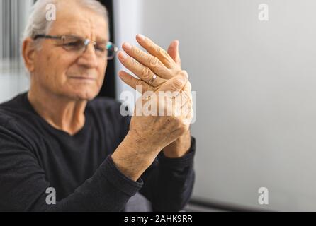 elderly person massaging his hands. Elderly Person With Painful Hand . Old man have a problem with circulation hands. Place for text Stock Photo