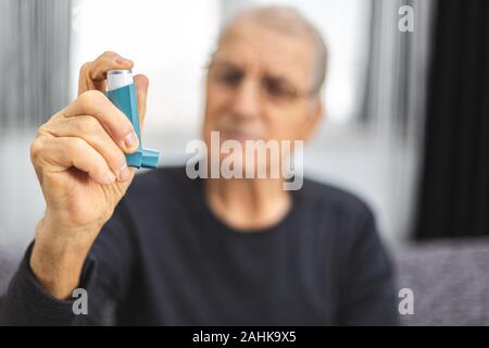 Elderly person using an asthma spray. Senior man ready for using an asthma inhaler Stock Photo