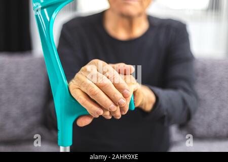 Elderly person standing with hands resting on medical walking stick. Concept of person with immobility, joints, rheumatism problem. Stock Photo