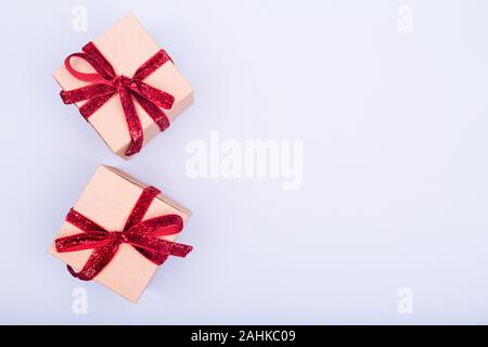 Craft boxes with red ribbon bows. Holiday, Christmas, New Year and Valentine day eco-friendly wrapping concept. Trendy minimalistic flat lay design background. Horizontal Stock Photo