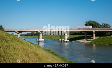 Bridge view and truck on the bridge. Pictured is a blue sky and a river, and a truck crossing the bridge over the river. Stock Photo