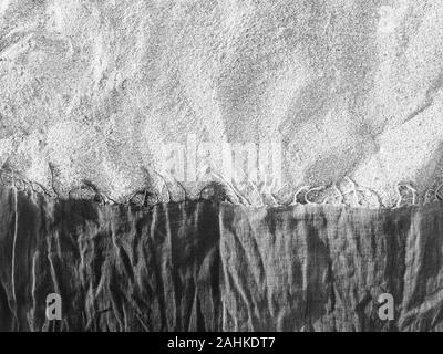 Sand on the beach Black and white photo of a checkered shawl lying on the sand Stock Photo