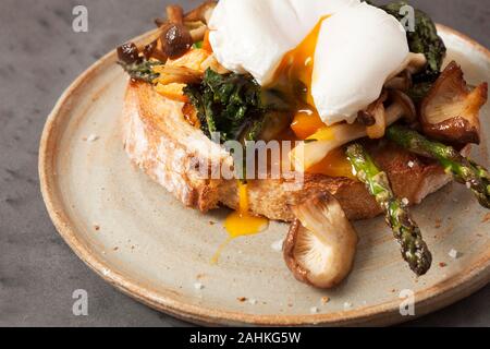 A poached egg on sourdough bread with asparagus and mushrooms Stock Photo