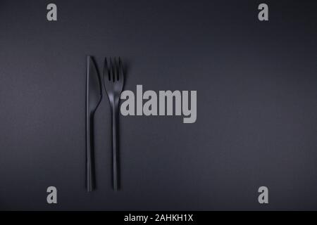 Black plastic fork and knife on black background. Stock Photo